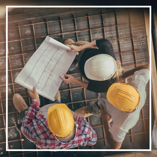 Contractors studying blueprints for foundation repair on a construction site in Dallas, TX