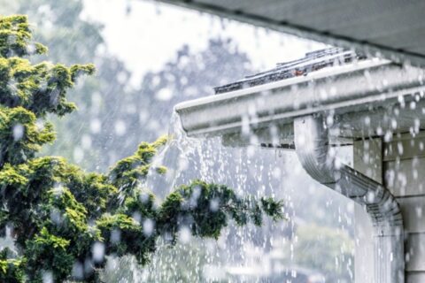 Heavy rain pouring off a home's gutter system in Dallas, TX