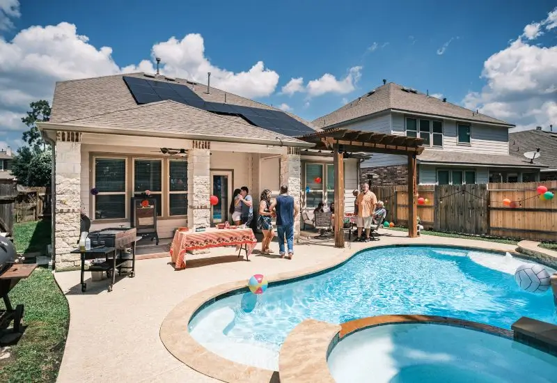 Backyard pool party with guests, pergola, and solar panels in Dallas, TX 