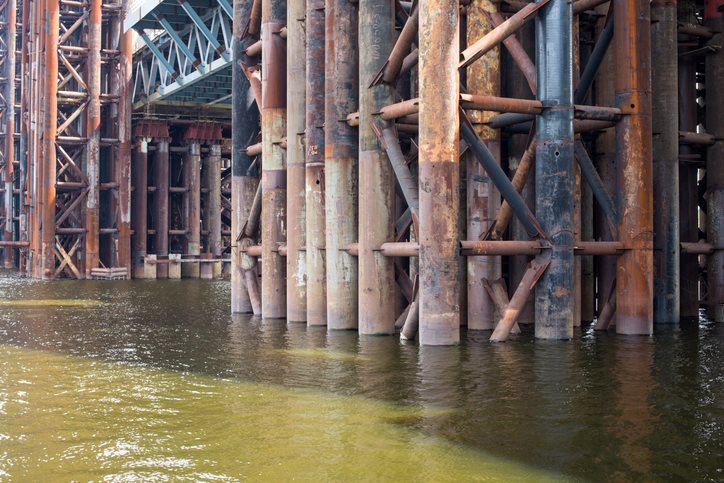 Rusty steel bridge supports in water in Dallas, TX
